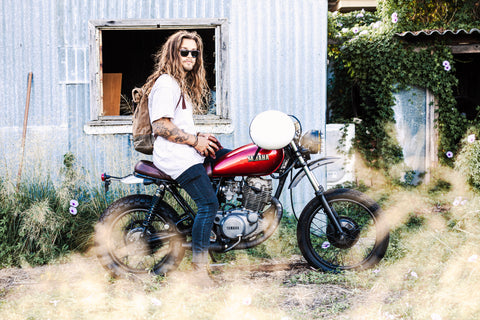 Person sitting on a red motorcycle wearing Vilo wooden sunglasses